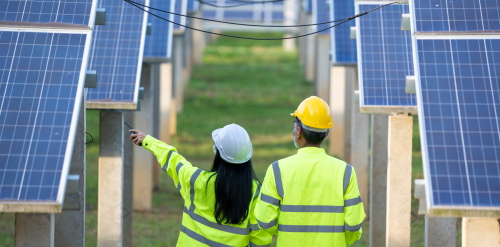 This image: a photo of a man and a woman wearing
							 PPE whilst walking between panels on a solar farm.
							 The map: The map shows the southern half of the Isle of Man, with
							 an orange map marker indicating the proposed site location just
							 north of Castletown.